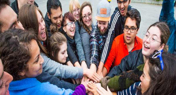 group of students in a circle putting hands on top of each other